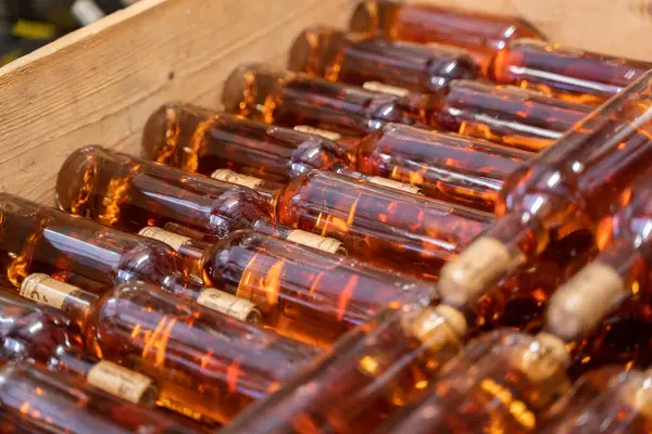 stock image Close-up of several bottles of wine stacked neatly in a wooden crate, ready for storage or shipment.