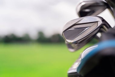 Görüntü, güzel bulanık yeşil bir manzaraya karşı çeşitli golf sopalarını gösteriyor. Spor meraklıları için mükemmel.
