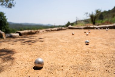 Dışarıda oynanan Petanque oyununun güzel bir sahnesi. Güneşin altındaki kumlu bir korta metal toplar saçılıyor.