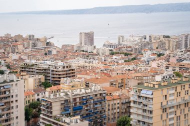Arkasında binalar ve deniz olan şehir manzarası, modern bir kentsel alanı betimliyor.
