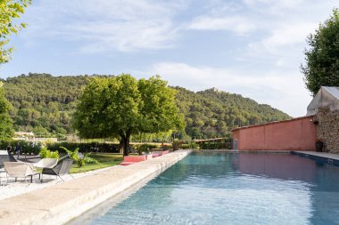 Serene poolside scene with lush green hills, blue skies, and scenic beauty perfect for relaxing vacations.