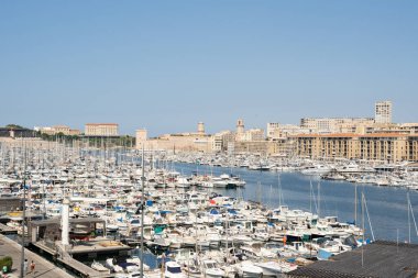 Güneşli bir günde limana çok sayıda tekne yanaştı ve arka planda tarihi binalar görülebiliyor..