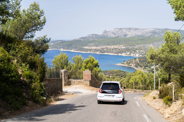 Белый автомобиль едет по прибрежной дороге с видом на море и горы, олицетворяя дух приключений