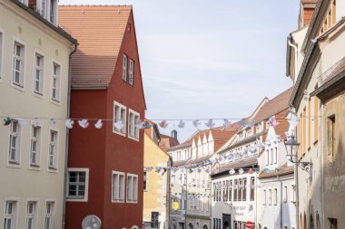 Büyüleyici bir Avrupa kasabasında dekoratif çelenklerle süslenmiş canlı binaların bulunduğu pitoresk bir cadde.