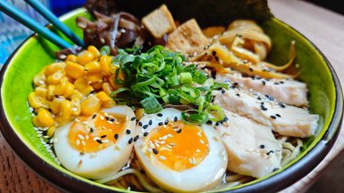 Bir kase ramen, haşlanmış yumurta, tavuk dilimleri, mısır, yeşil soğan ve susamlı çorba. Japon mutfağı, konforlu yemek ve gurme yemeği kavramı
