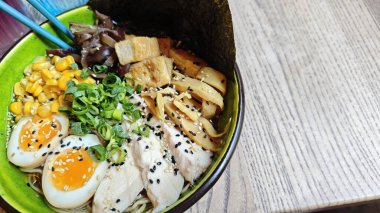 Yumuşak yumurta, tavuk, tofu, mısır, yosun ve yeşil kasede yeşil soğan ile Japon ramen çorbası. Geleneksel Asya mutfağı, konforlu yemek ve doyurucu restoran yemeği kavramı