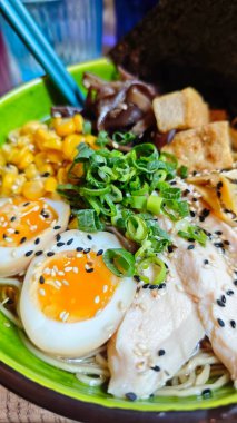 Bir kase ramen, ramen, yumurta, tavuk, mısır, tofu ve yeşil soğan, yakından görüş. Asya mutfağı ve sokak yemekleri konsepti