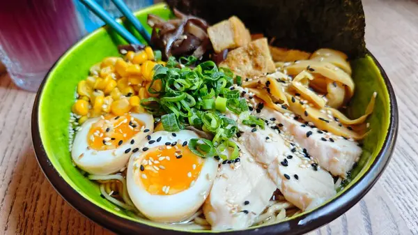 Yumurta, mısır, tavuk, tofu, mantar ve soğanlı renkli ramen kasesi. Japon mutfağı, konforlu yiyecekler ve lezzetli ev yapımı yemekler.