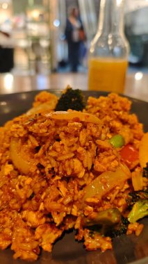 Restoran ortamında servis edilen sebzeli ve tavuklu baharatlı pilav. Asya mutfağı, sokak yemekleri ve geleneksel sıcak yemek kavramı.