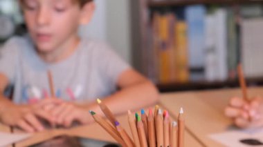 Çocuklar evde konsept eğitimde renkli kalemlerle yazılar çizerek okula geri dönüyorlar.