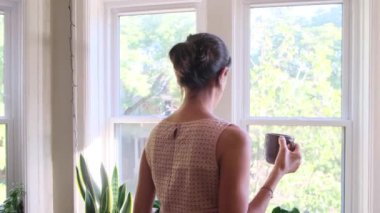 Çekici bir bayanın evde kahvesini yudumlarken görüntüsü.