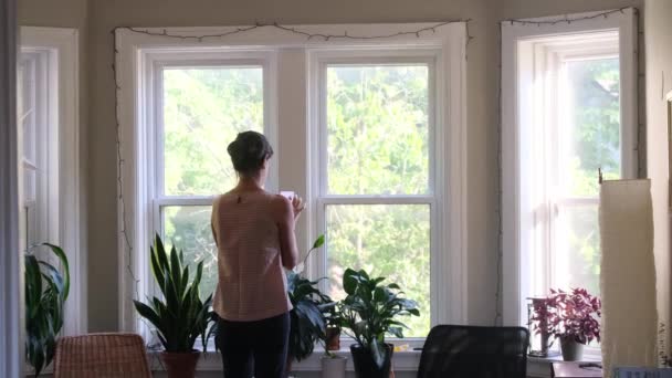 Evin Penceresinin Önünde Akıllı Telefonu Olan Genç Bir Kadının Arka — Stok video