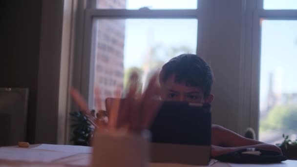 男の子はデスクでデジタルタブレットのコンピュータを使用しています — ストック動画