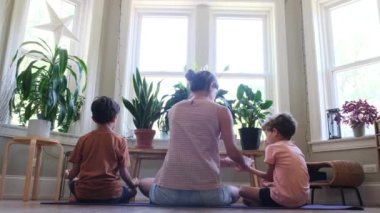 Genç anne çocuklara yoga öğretiyor. Evde yoga, asanas, sağlıklı yaşam tarzı, dengeli farkındalık eğitimi. Kavramları...