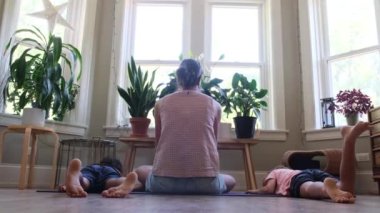 Genç anne çocuklara yoga öğretiyor. Evde yoga, asanas, sağlıklı yaşam tarzı, dengeli farkındalık eğitimi. Kavramları...