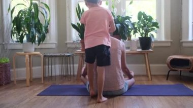  Yoga yapan bir kadın ve oğlu ona doğru geliyor.  