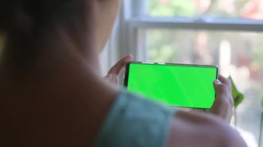 Akıllı telefonlu, yeşil ekran krom anahtarlı bir kadın sabahları ekranda telefona dokunuyor ve onunla etkileşime geçiyor.