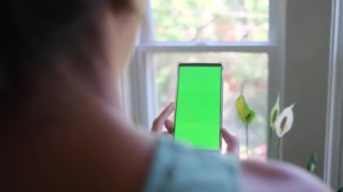 Akıllı telefonlu, yeşil ekran krom anahtarlı bir kadın sabahları ekranda telefona dokunuyor ve onunla etkileşime geçiyor.