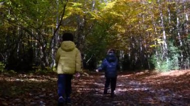 Ormanda sonbahar kış ortamı çocuklar anneleri sağlıklı yürüme oyunu oynuyorlar mutlu aile kavramı.