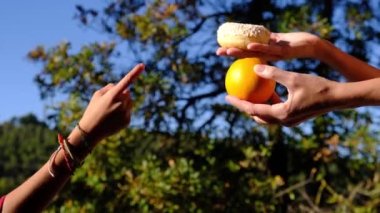 Anne ve oğlunun elleri meyve, endüstriyel hamur işi ve donut arasında seçim yapıyor. Sağlıklı meyve ve abur cubur arasında seçim yapmak zararlı beslenme, diyet konsepti yoluyla yararlı. Gıda eğitimi 