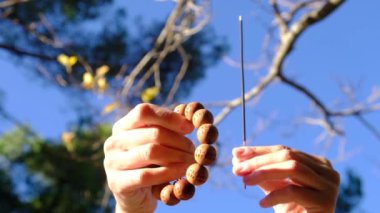  Taoist Budist tütsülü kadın eli, doğal çevre kavramında güneş ışınları ile tespih, huzur, sükunet, farkındalık yoga, meditasyon.