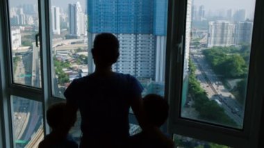 Pencereye yakın duran çocuklu kadın silueti