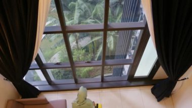 Müslüman turist kadın valiziyle pencerenin önünde dikiliyor.