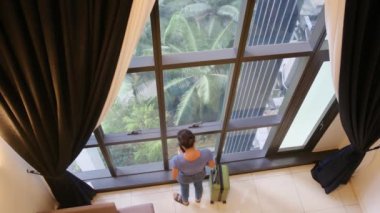 Elinde bavuluyla pencerenin yanında duran turist kadının en iyi görüntüsü.