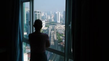 Modern şehrin penceresinde duran kadın