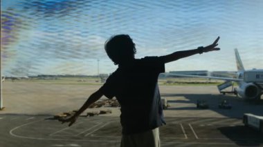 Çocuk arka planda uçakla havaalanında eğleniyor. 