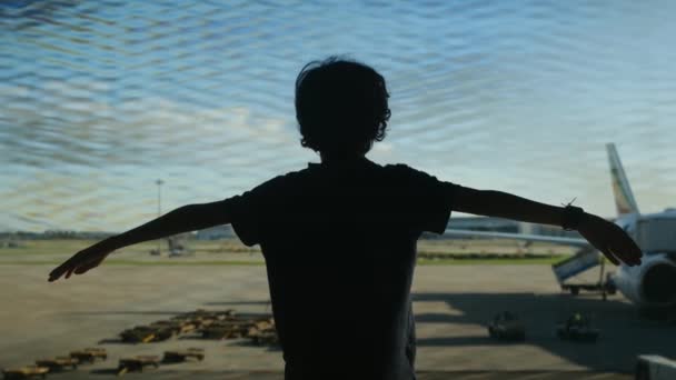 バックグラウンドで飛行機で空港で楽しんでいる少年 — ストック動画