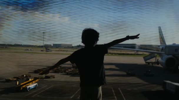バックグラウンドで飛行機で空港で楽しんでいる少年 — ストック動画