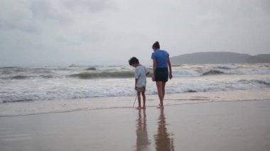 Çocuk sahilde kadınla
