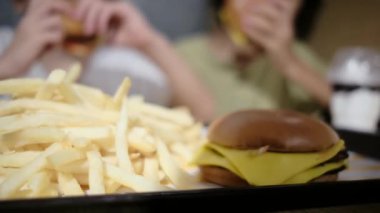 İnsanlar masada fast food yiyor.