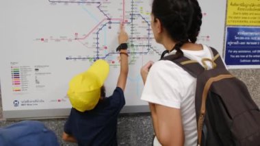 Anne ve çocuklar şehirdeki metro sisteminin haritasını izliyorlar.