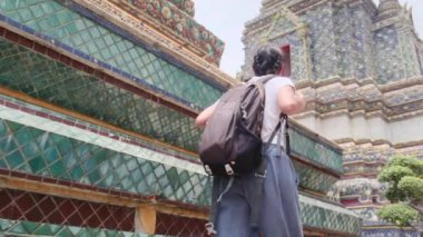 Sırt çantalı kadın gezginin arkasında Güneydoğu Asya 'daki Budist kültürünün cazibe mimari geçidinde yürüyor.