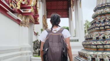 Sırt çantalı kadın gezginin arkasında Güneydoğu Asya 'daki Budist kültürünün cazibe mimari geçidinde yürüyor.