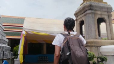Sırt çantalı kadın gezginin arkasında Güneydoğu Asya 'daki Budist kültürünün cazibe mimari geçidinde yürüyor.