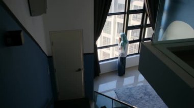 tesettürlü çekici müslüman kadın pencerenin yanında cep telefonu kullanıyor..