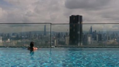 şehir silueti üzerinde sonsuz havuzda yüzen seyahat eden bir kadın. 
