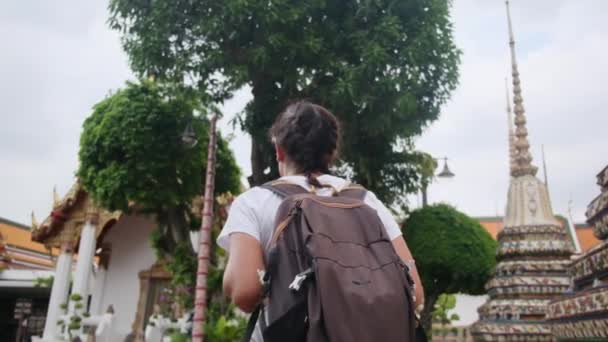 東南アジアの仏教文化のアトラクション建築パゴダを歩くバックパック旅行の背後にある女性旅行者 — ストック動画