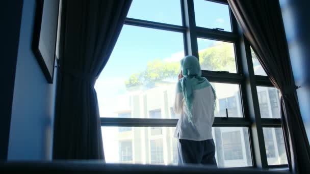 窓の近くの携帯電話を使用してヒジャブの魅力的なイスラム教徒の女性 — ストック動画