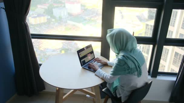 窓の近くのラップトップを使用してヒジャブの魅力的なイスラム教徒の女性 — ストック動画