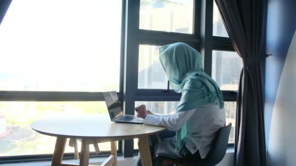 在窗户附近使用笔记本电脑的有魅力的头巾穆斯林妇女 — 图库视频影像