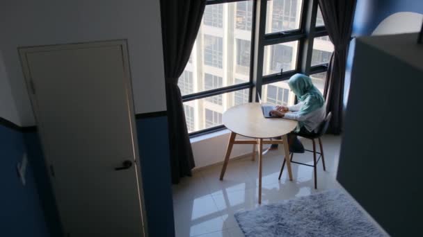 Pencerenin Yanında Dizüstü Bilgisayar Kullanan Tesettürlü Çekici Müslüman Kadın — Stok video