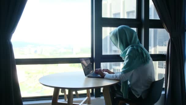 在窗户附近使用笔记本电脑的有魅力的头巾穆斯林妇女 — 图库视频影像