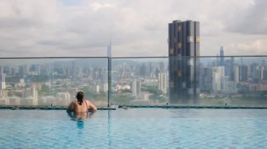 şehir silueti üzerinde sonsuz havuzda yüzen seyahat eden bir kadın. 