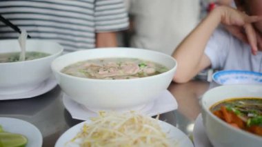 Çocuklar masada erişte çorbası içer.