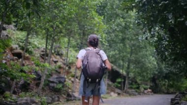 Sırt çantalı kadın turist, tropikal dağda yürüyüş yapıyor.