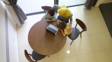 tesettürlü Müslüman anne ve çocukları, 5 ve 8, samimi bir Ramazan bayramı görüntüsü için bir dizüstü bilgisayarla bağlanıyorlar, teknolojiyle aralarındaki mesafeleri eşitliyorlar.